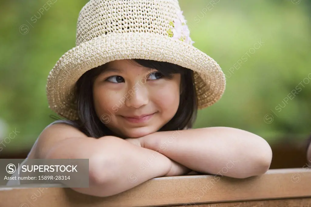 Young Asian girl wearing straw hat and smiling outdoors