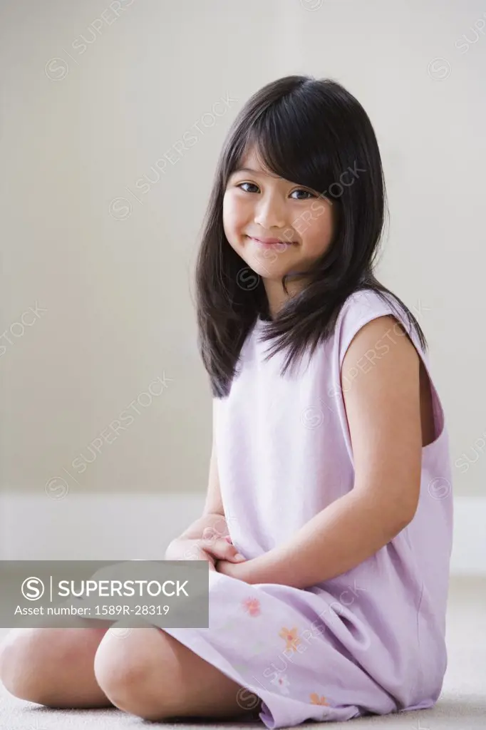 Young Asian girl sitting on floor smiling