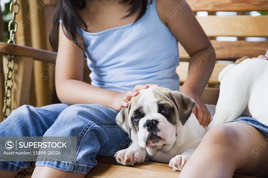 Girl petting puppy on porch swing