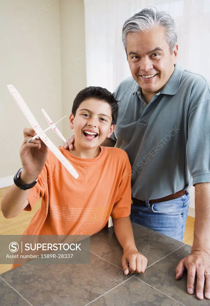 Hispanic father and son holding model airplane