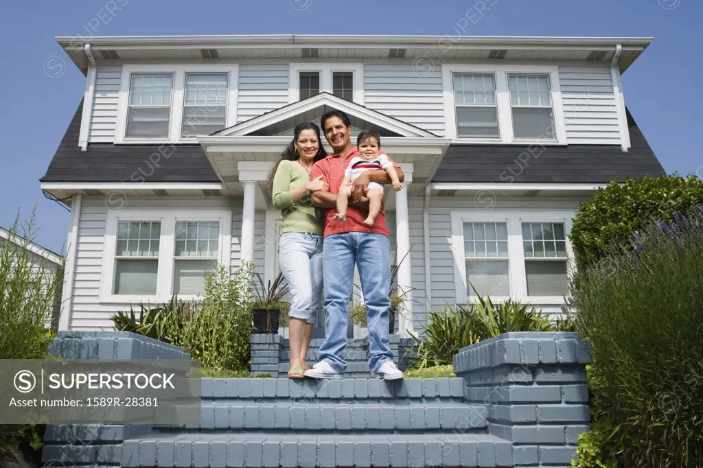 Hispanic family standing on steps in front of house