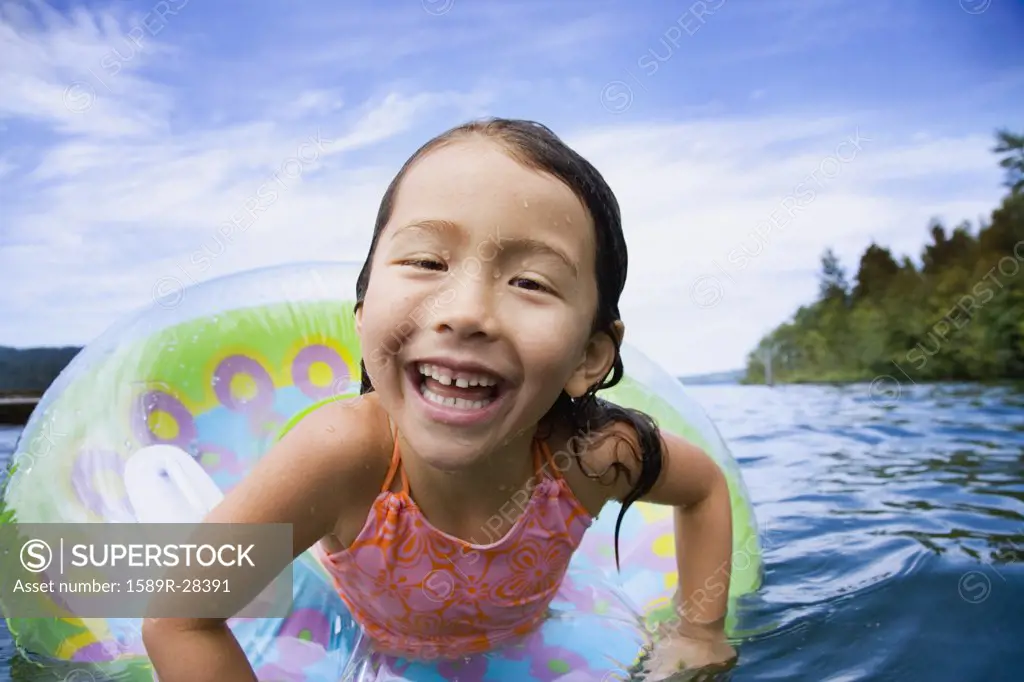 Close up of young Asian girl smiling in inner tube in water
