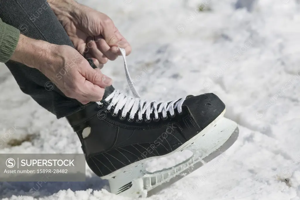 Close up of man lacing ice skate