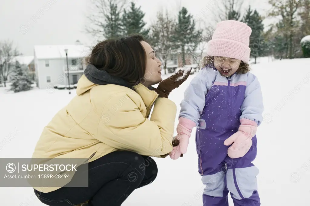 Mother and young daughter playing with snow