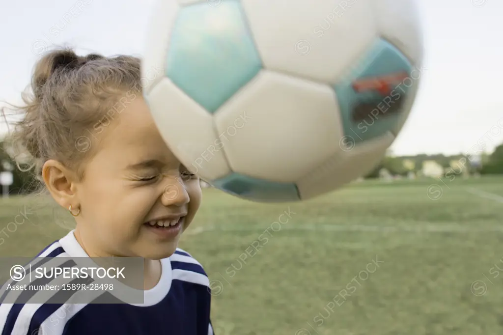 Young girl bouncing soccer ball off head