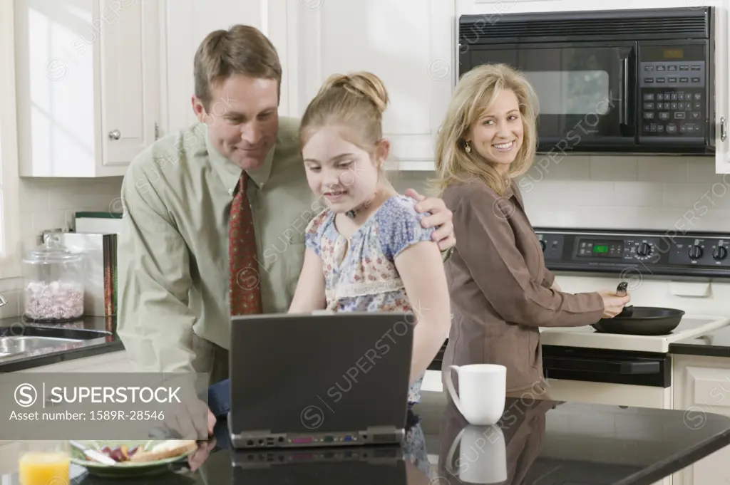 Family making breakfast and looking at laptop