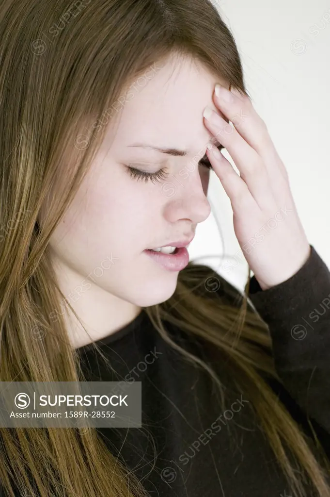 Young woman touching forehead with eyes closed