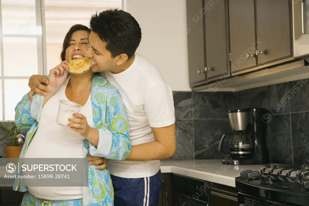 Pregnant couple in pajamas in kitchen