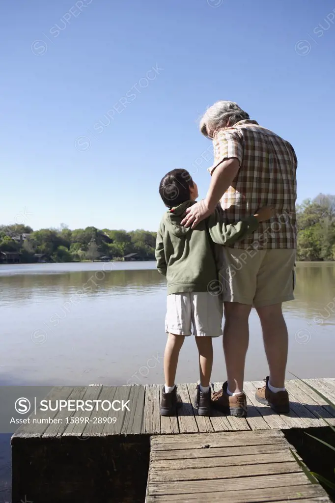 Grandfather and grandson standing on wooden dock