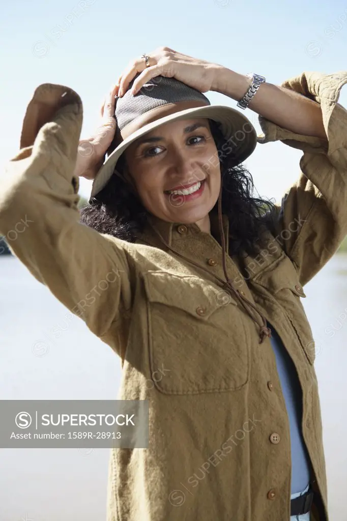 Hispanic woman smiling with hands on head outdoors
