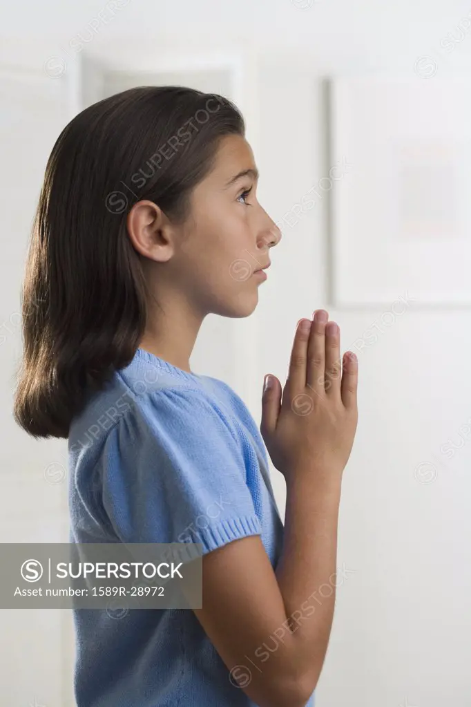 Hispanic girl praying indoors