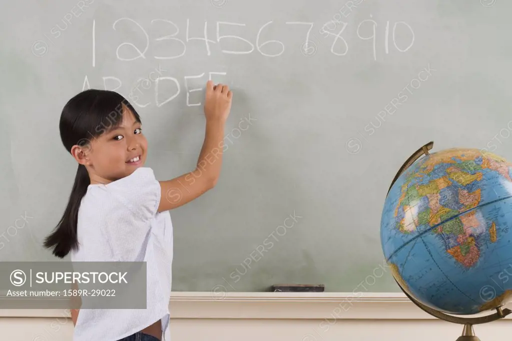 Young girl writing on blackboard