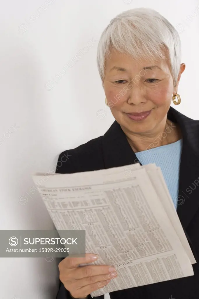 Senior Asian businesswoman reading newspaper