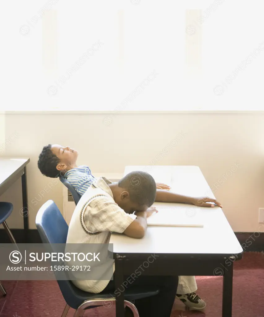 Two young students asleep at desk in classroom