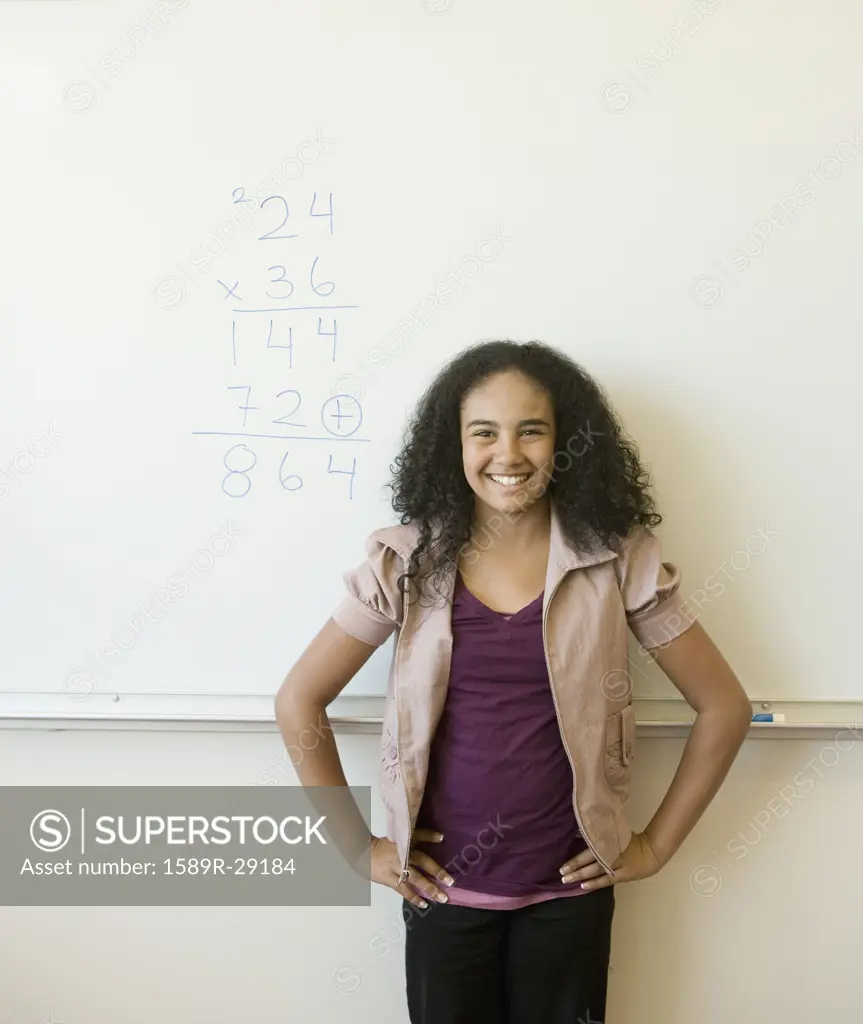African girl smiling in front of whiteboard in classroom