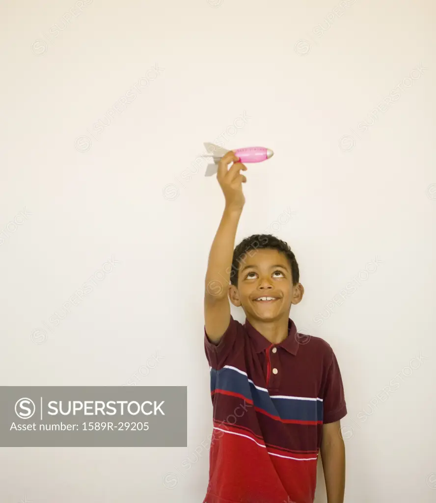Studio shot of boy playing with toy missile