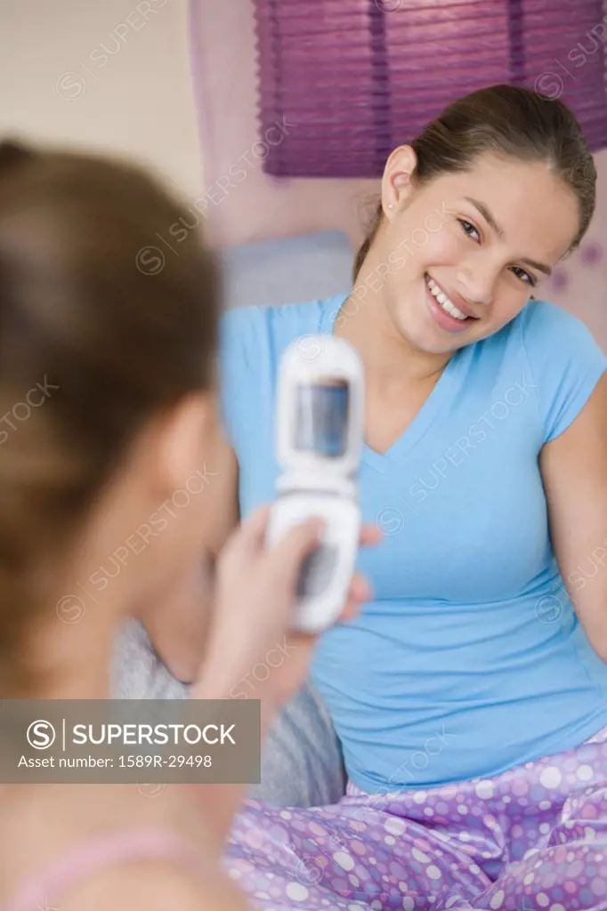 Girl taking sister's photograph with cell phone