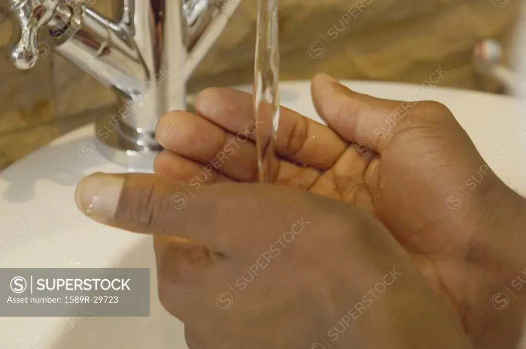 Close up of African man's hands under water in sink