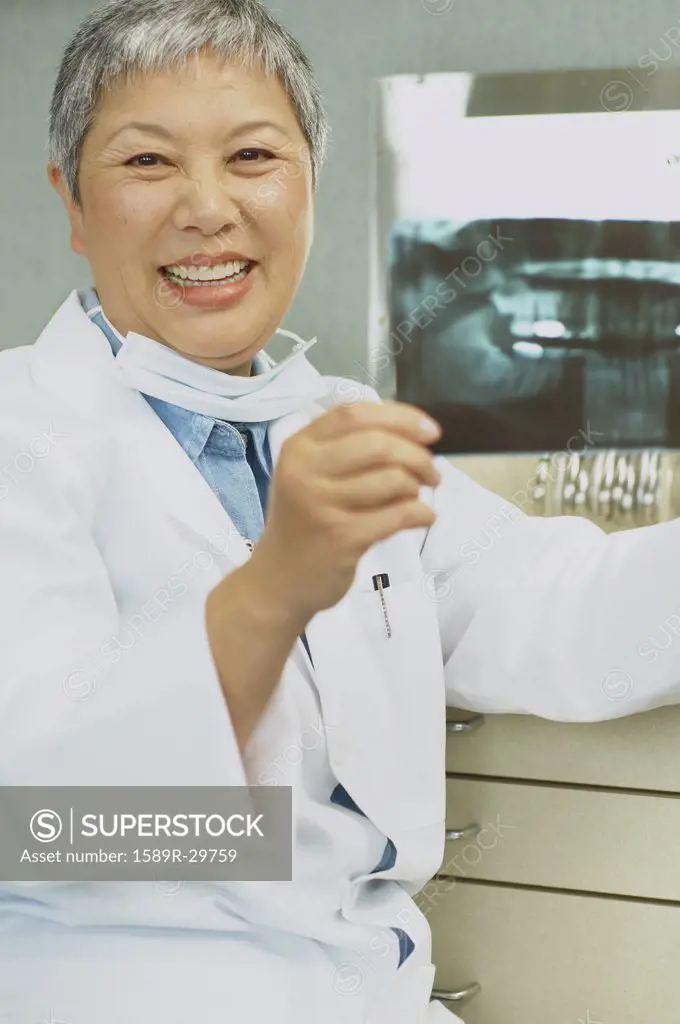 Senior Asian female dentist looking at x-rays