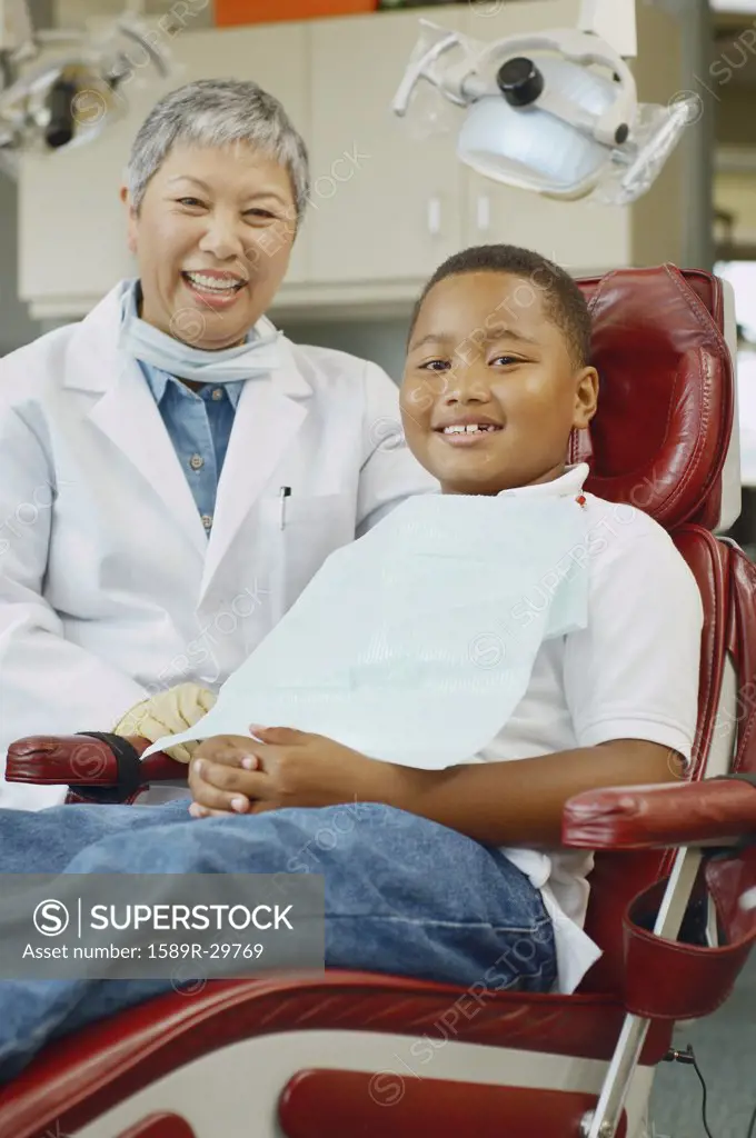 Senior Asian female dentist and African boy in dentist's chair