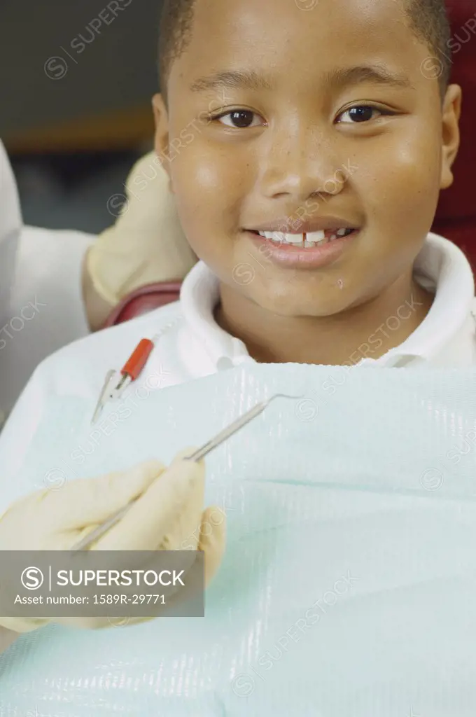 Close up of dentist's hand holding dental tool next to boy's mouth