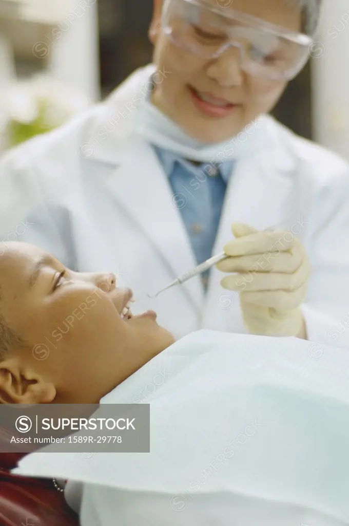Senior Asian female dentist working on African boy