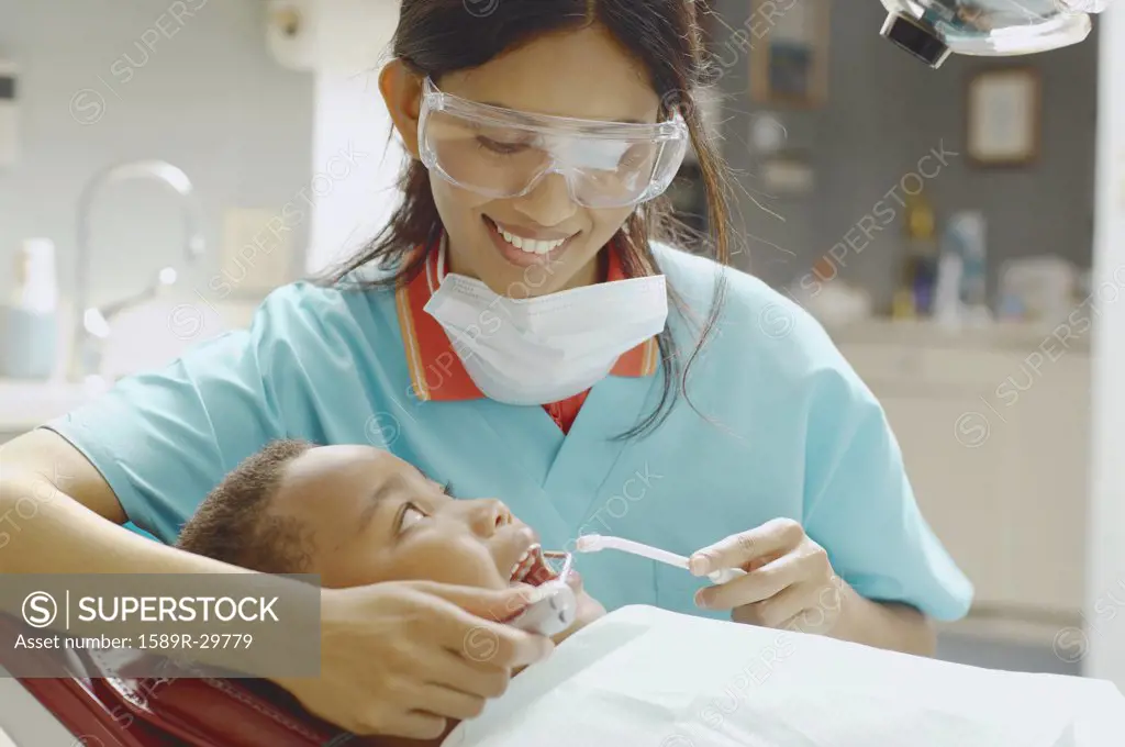 Indian female dental assistant working on African boy