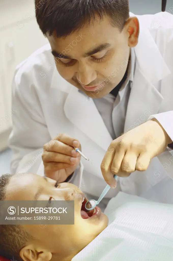Indian male dentist working on African boy