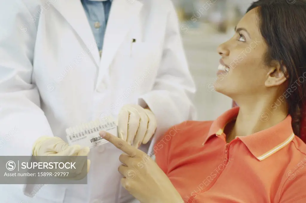 Dental patient choosing tooth color sample from dentist