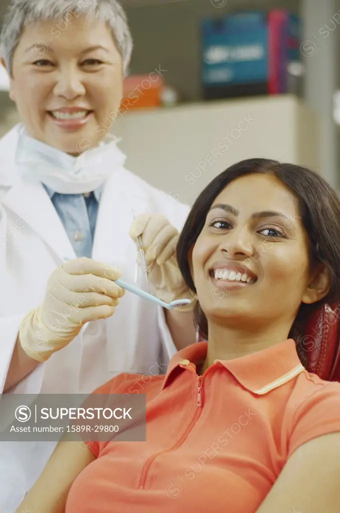 Senior Asian female dentist next to Indian female patient
