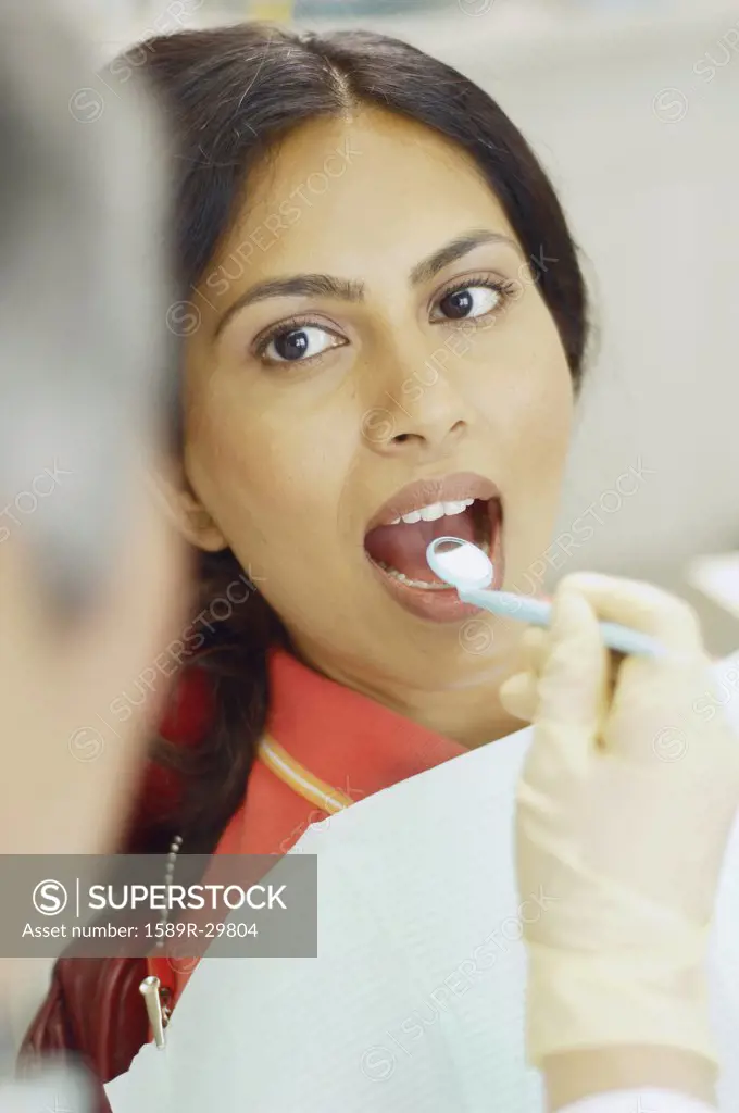 Dentist holding dental mirror in female patient's mouth
