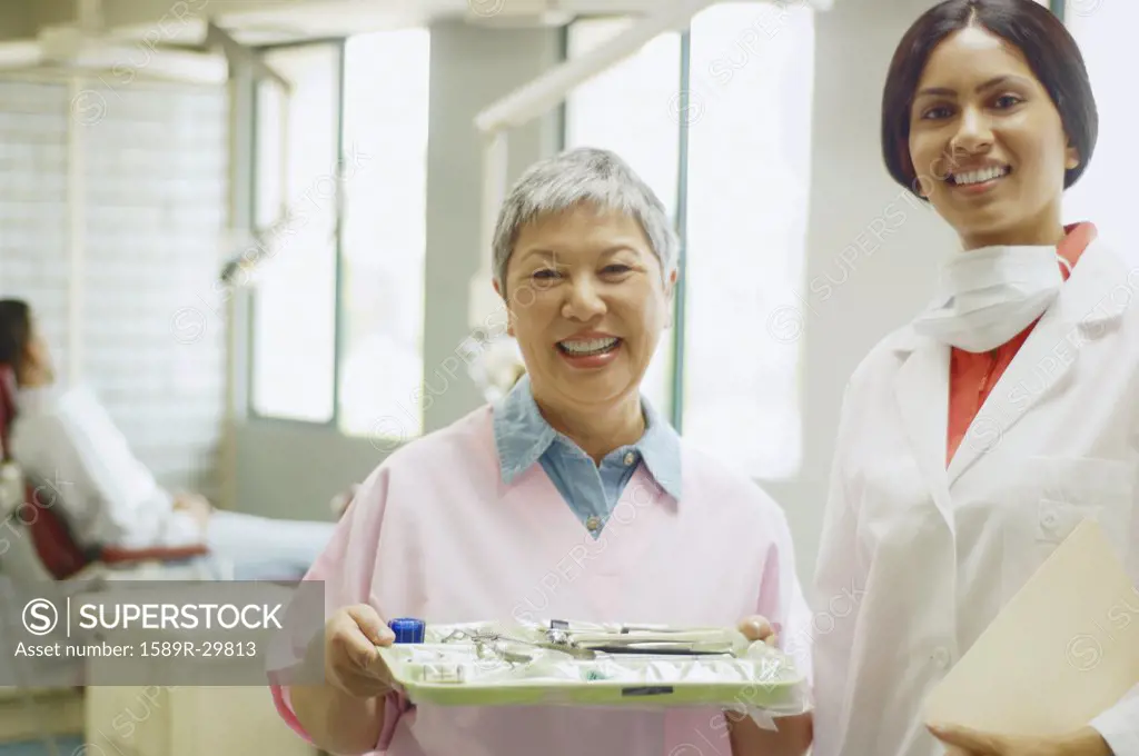 Indian female dentist and senior Asian female dental assistant smiling