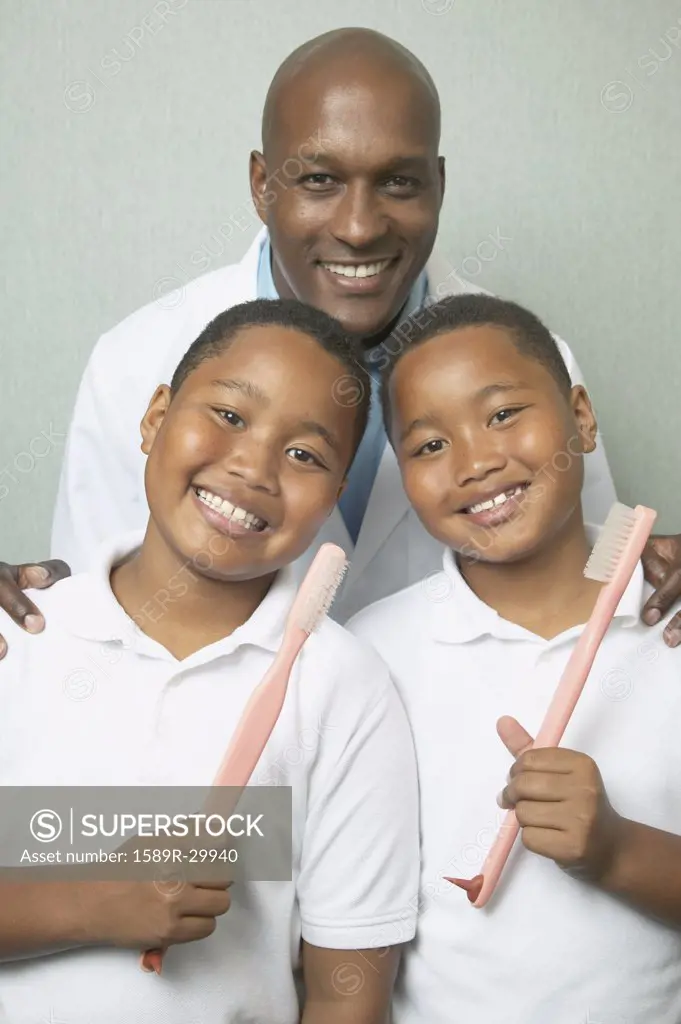 African male dentist with twin boys holding toothbrushes