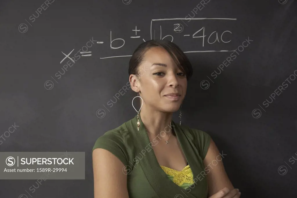 African female student next to math problem on blackboard
