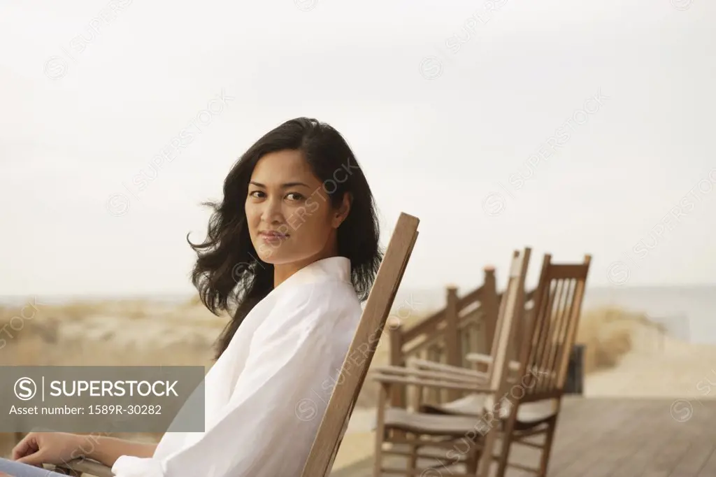 Asian woman sitting on deck at beach