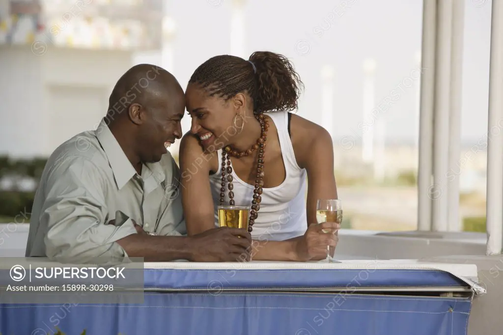 African couple smiling at each other with cocktails