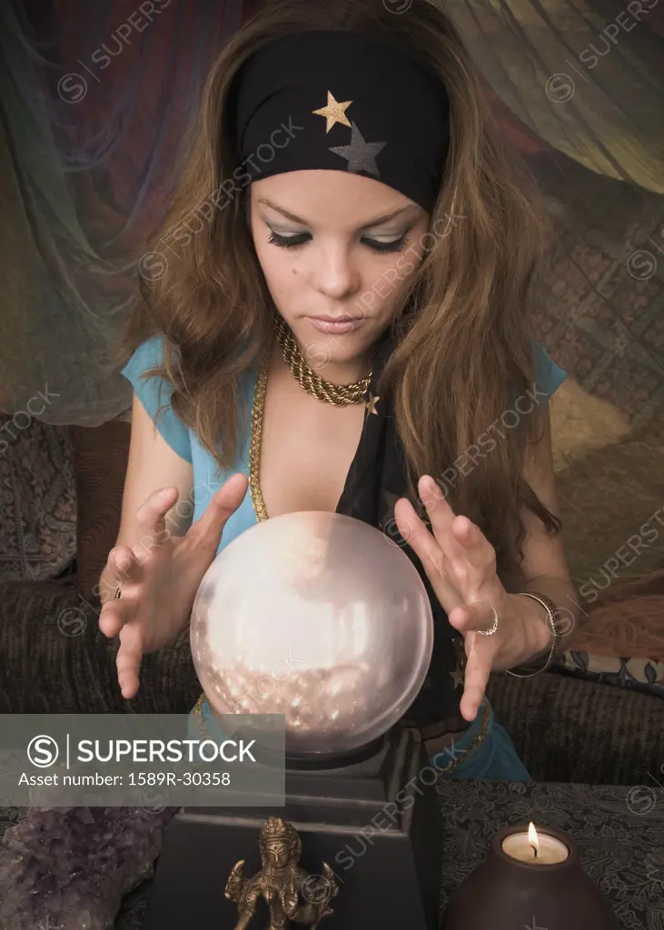 Woman dressed at fortune teller looking into crystal ball
