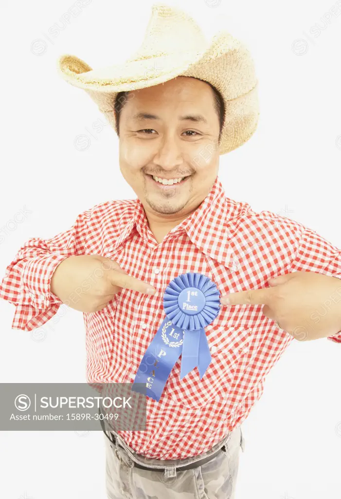 Studio shot of Asian man wearing cowboy hat and blue ribbon
