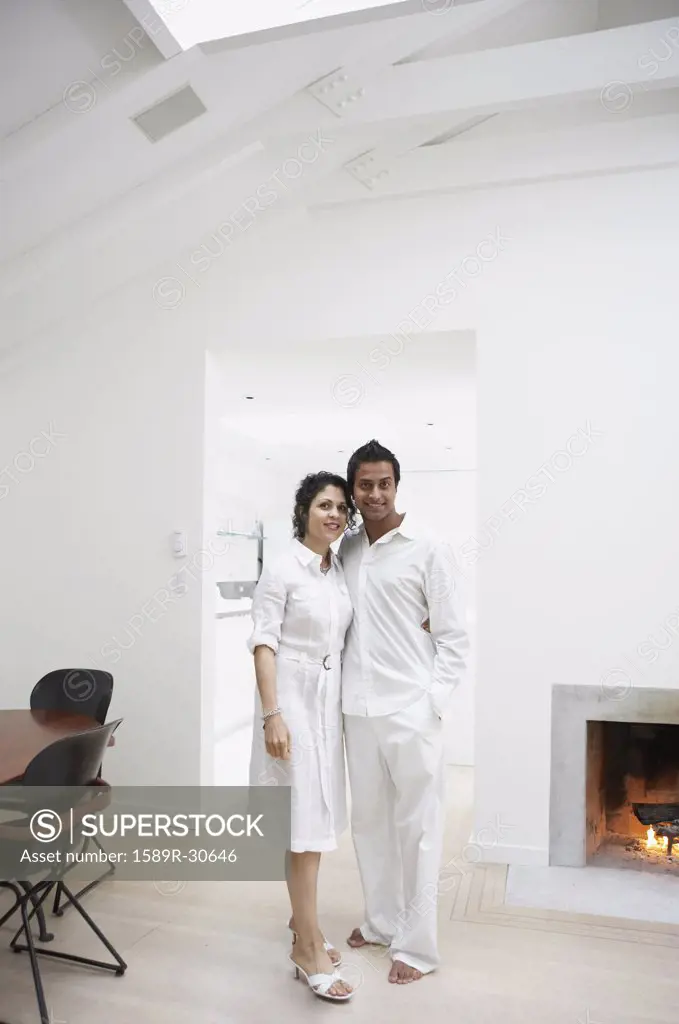 Middle Eastern couple hugging next to fireplace