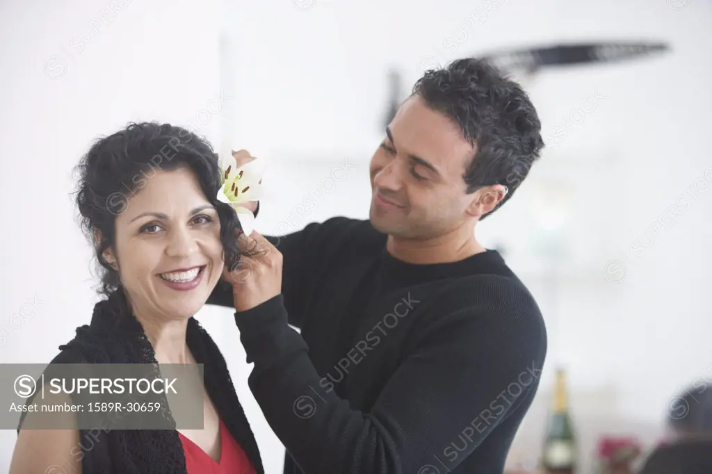 Man putting flower in woman's hair