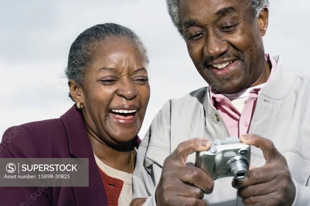 Senior African couple smiling and looking at digital camera