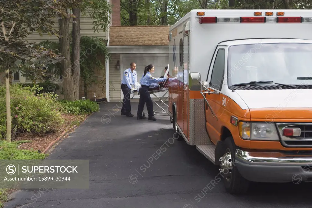 Paramedics putting person in ambulance in driveway