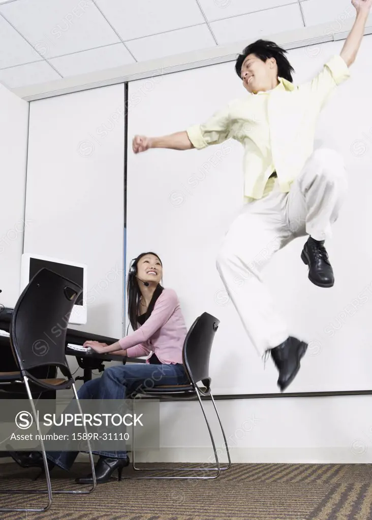 Asian man jumping next to Asian female computer service technician