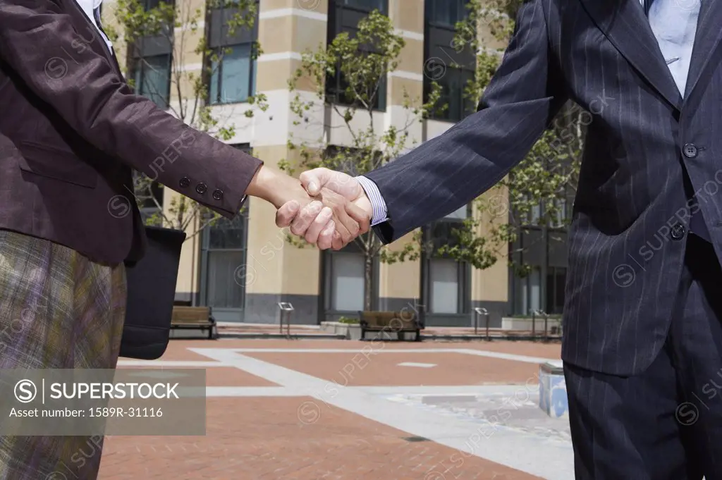 Businesswoman and businessman shaking hands outdoors