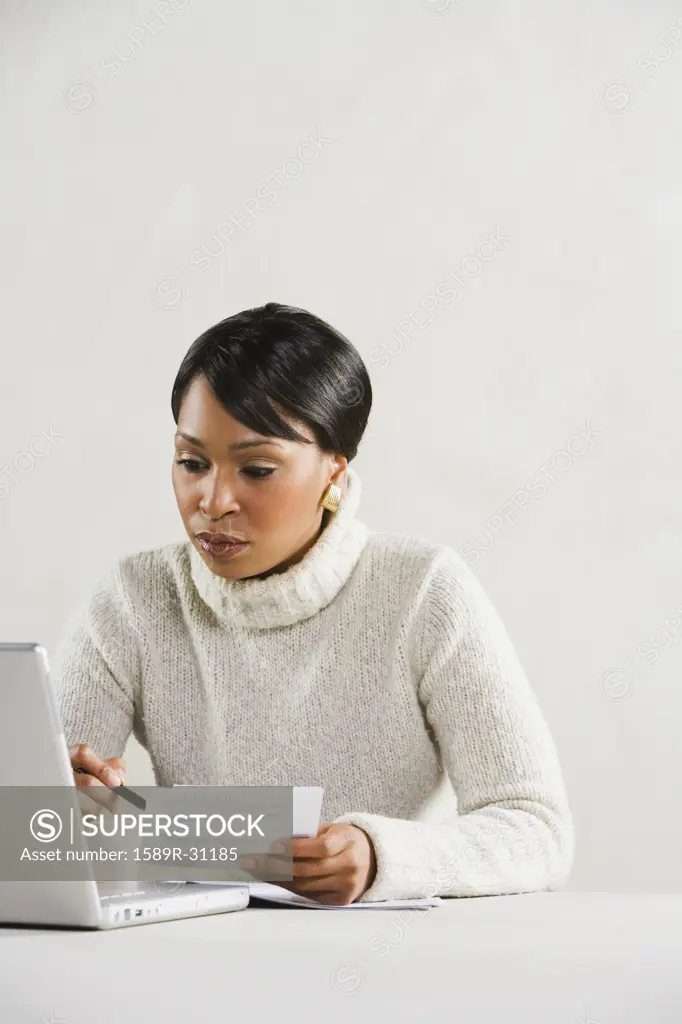Studio shot of African woman with laptop and paperwork