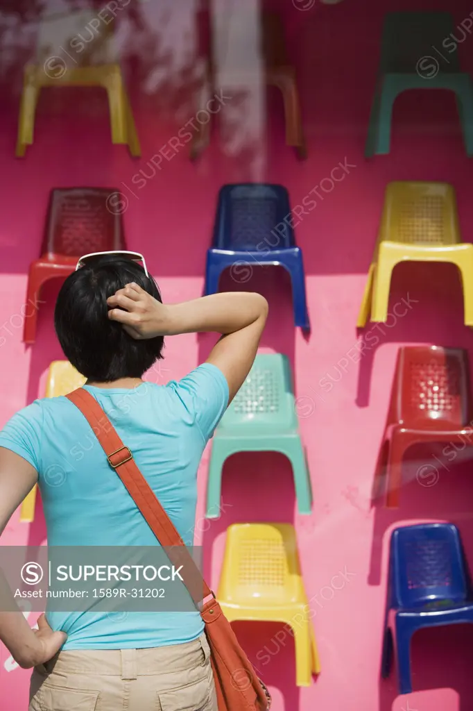 Woman looking at plastic chairs in store window