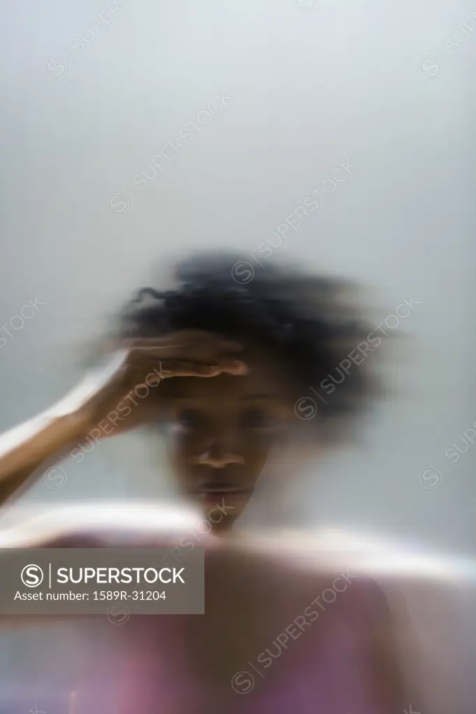 African woman peering through frosted window