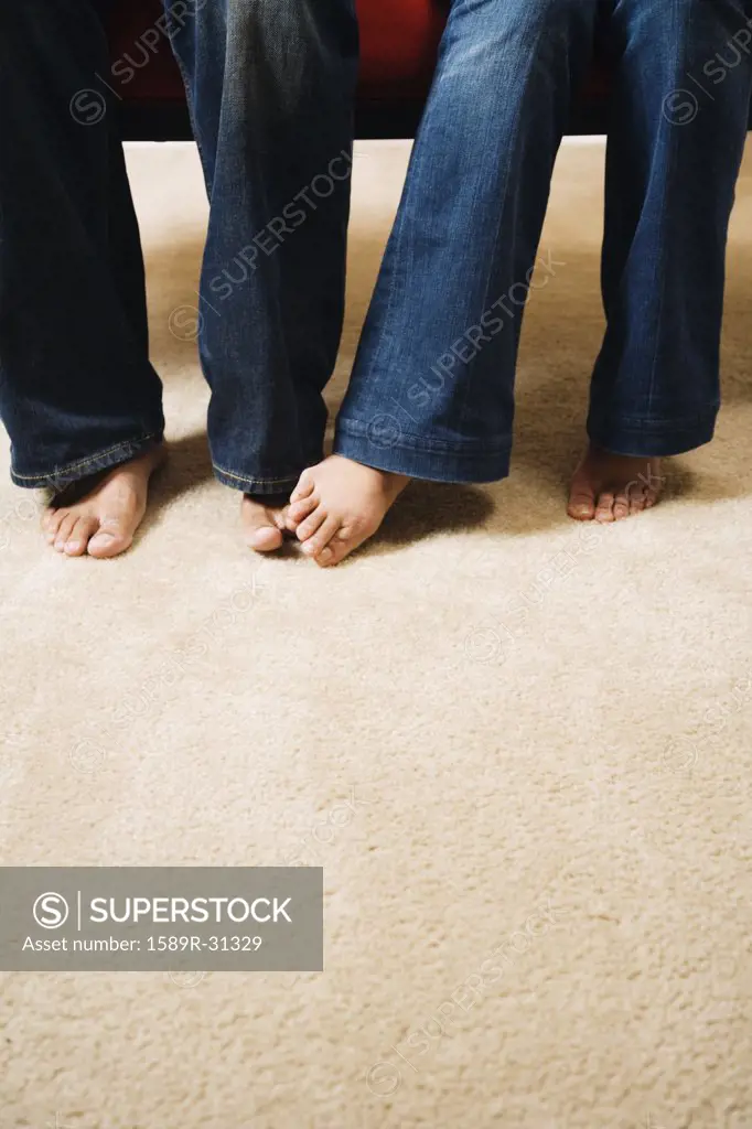 Close up of couple's bare feet touching carpet