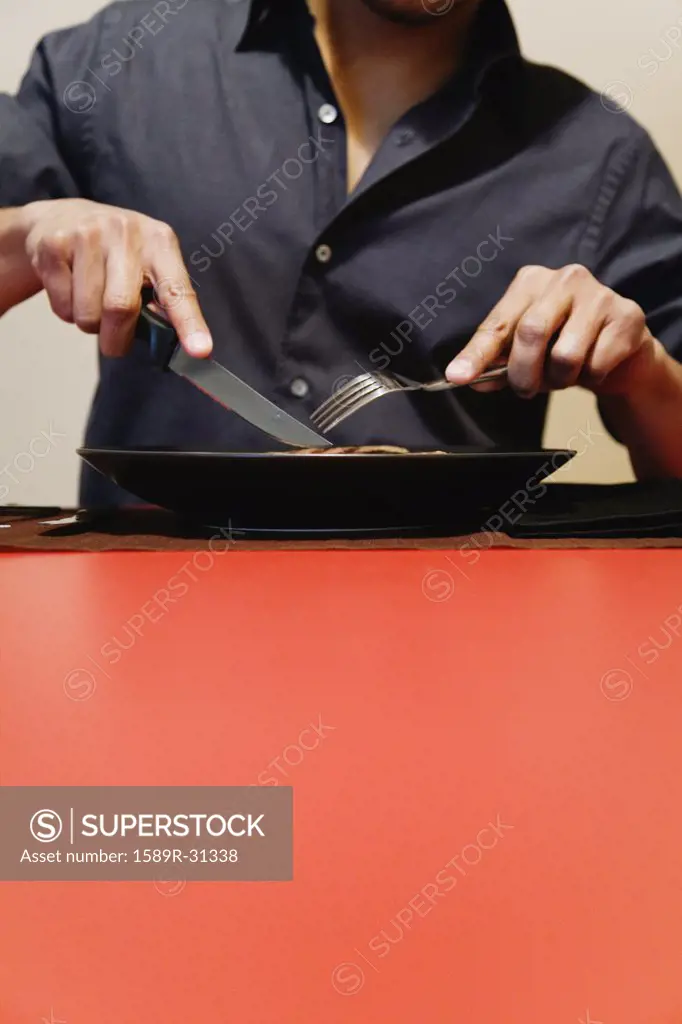 Man cutting meat on plate at table