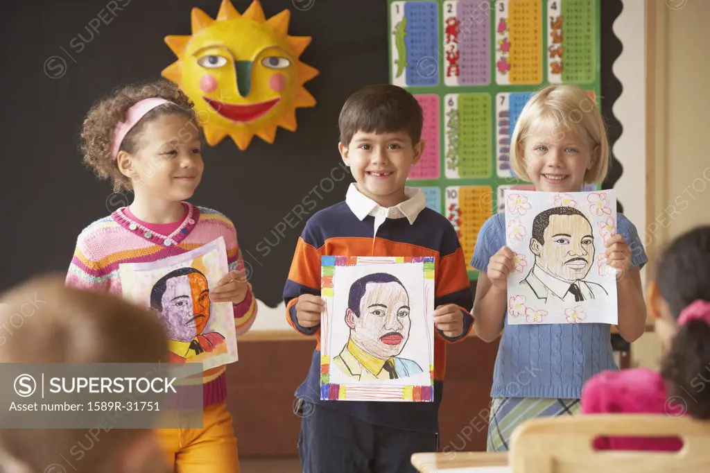 Multi-ethnic students holding up pictures in class